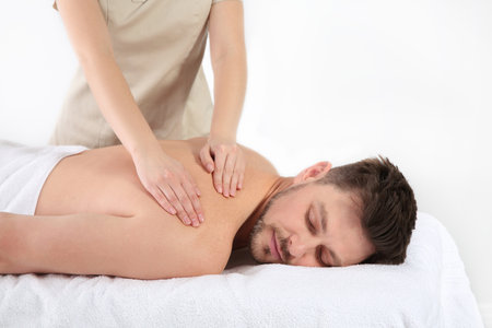 Handsome man receiving back massage on white background. Spa serviceの写真素材