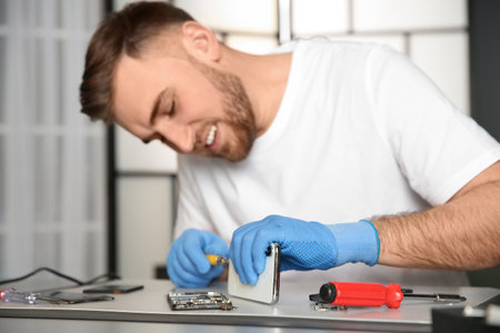 Technician repairing mobile phone at table in workshop, closeupの写真素材