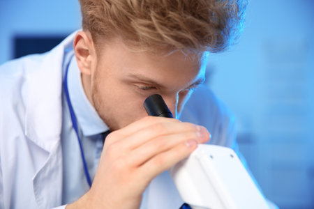 Male scientist using modern microscope in chemistry laboratoryの写真素材