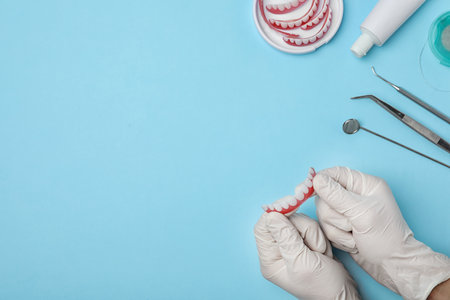 Dentist holding tooth prosthesis on color background, top view. Space for textの写真素材
