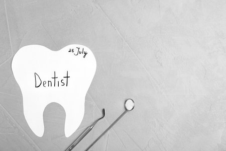Paper tooth cutout and dentist tools on gray background, flat lay. Space for textの写真素材