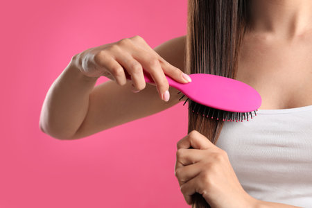 Woman with hair brush on color background, closeupの写真素材