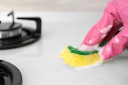 Person cleaning gas stove with sponge, closeupの写真素材