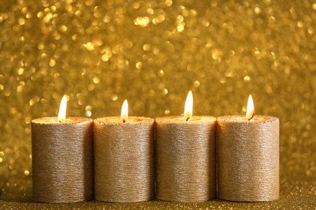 Stylish burning candles on golden shining background, space for textの写真素材