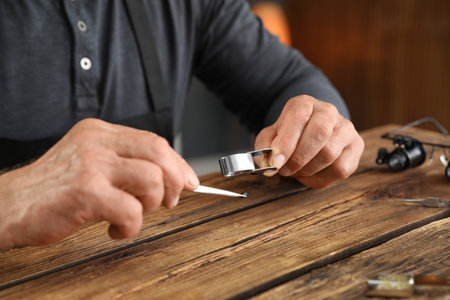 Male jeweler evaluating precious gemstone at table in workshop, closeupの写真素材
