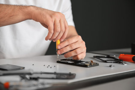 Technician repairing mobile phone at table, closeupの写真素材