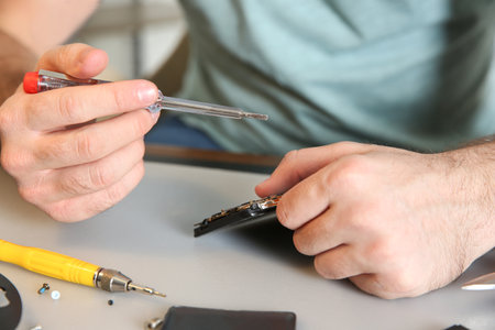 Technician repairing mobile phone at table, closeupの写真素材