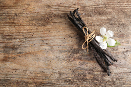 Flat lay composition with aromatic vanilla sticks and flower on wooden background. Space for textの写真素材