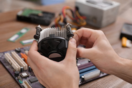 Male technician repairing computer fan at table, closeupの写真素材