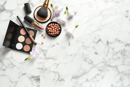 Many different makeup products and spring flowers on marble background, flat lay. Space for textの写真素材
