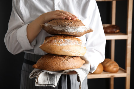 Baker holding loaves of bread indoors, closeupの写真素材
