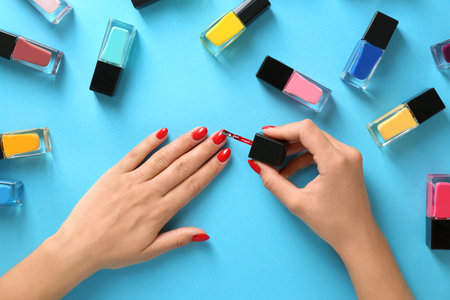 Woman applying bright nail polish on color background, top viewの写真素材