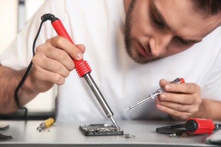 Technician repairing mobile phone at table, closeupの写真素材