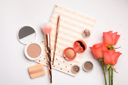 Flat lay composition with coral beauty accessories, notebook and roses on white backgroundの写真素材