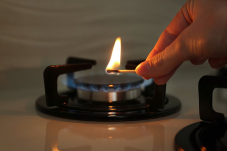 Woman lighting gas stove with match, closeupの写真素材