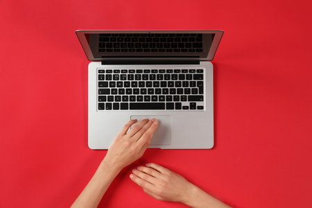 Woman using modern laptop at color table, top viewの写真素材