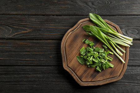 Board with wild garlic or ramson on wooden table, top view. Space for textの写真素材