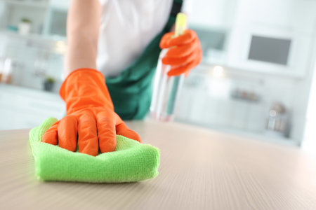 Worker in gloves cleaning table with rag, closeup. Space for textの写真素材