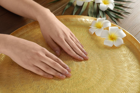 Woman soaking her hands in bowl with water and flowers on table, closeup. spa treatmentの写真素材