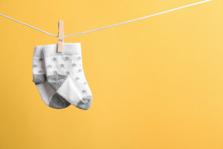 Small socks hanging on washing line against color background, space for text. baby accessoriesの写真素材