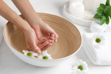 Woman soaking her hands in bowl of water and flowers on table, closeup with space for text. spa treatmentの写真素材