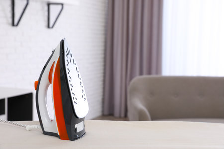 Modern electric iron on board indoors. Space for textの写真素材