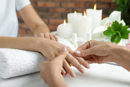 Cosmetologist massaging client's hand at table in spa salon, closeupの写真素材