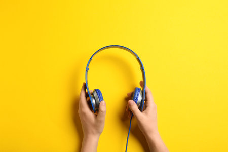 Woman holding stylish headphones on color background, closeupの写真素材