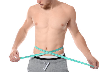 Young man with measuring tape showing his slim body on white background, closeupの写真素材