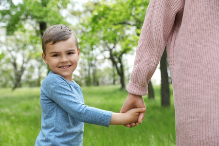 Happy little child holding hands with his mother in the park. family timeの写真素材