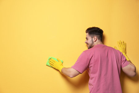 Man cleaning color wall with rag. Space for textの写真素材