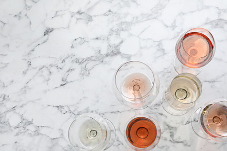 Different glasses with wine on marble background, flat lay. Space for textの写真素材