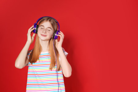 Teenage girl enjoying music in headphones on color background. Space for textの写真素材