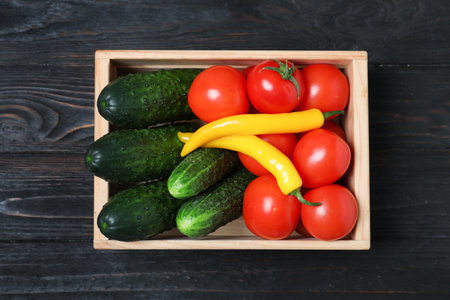 Wooden crate full of fresh vegetables on dark background, top viewの写真素材