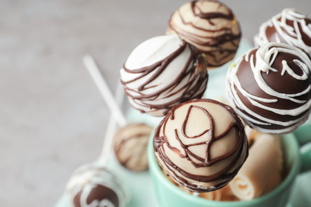 Yummy cake pops coated with chocolate in cup on table, closeup. Space for textの写真素材