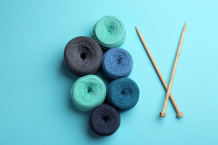 Clews of threads and knitting needles on color background, flat lay. Sewing stuff