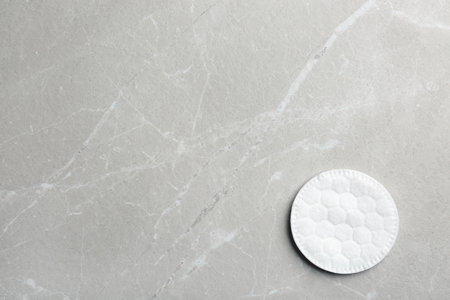 Cotton pad on gray background, top view. Space for text