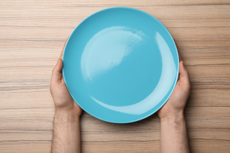 Man with empty plate at wooden table, top viewの写真素材