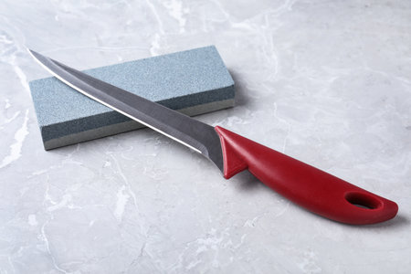 Boning knife and sharpening stone on gray background