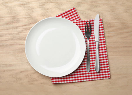 Stylish ceramic plate, napkin and cutlery on wooden background, flat layの写真素材