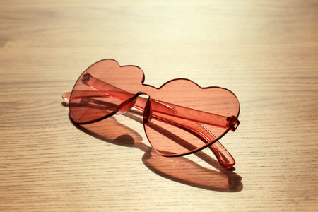 Stylish heart shaped sunglasses on wooden backgroundの写真素材