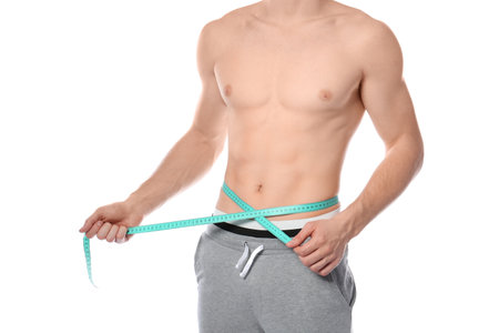 Young man with measuring tape showing his slim body on white background, closeupの写真素材