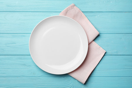 Stylish ceramic plate and napkin on color wooden background, flat layの写真素材