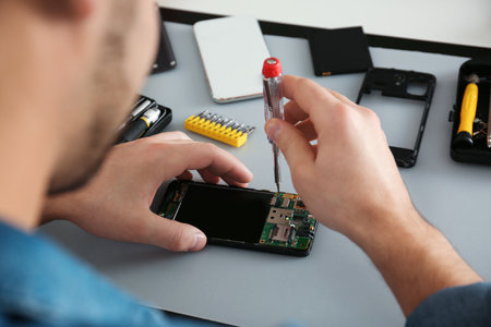 Technician repairing broken smartphone at table, closeupの写真素材