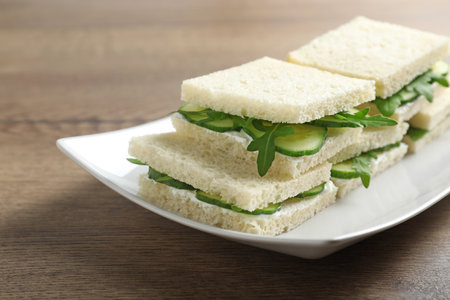 Plate with cucumber sandwiches on wooden table, closeup. Space for textの写真素材