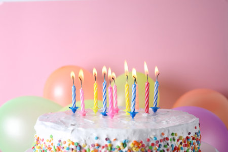 Birthday cake with burning candles and balloons on color background. Space for textの写真素材