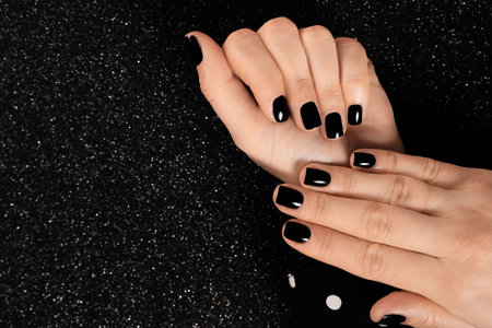 Woman with black manicure on dark background, top view. Space for textの写真素材