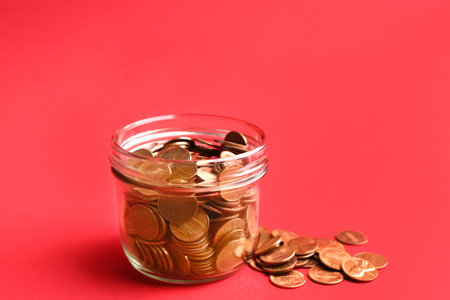 Glass jar and coins on color background. Space for textの写真素材