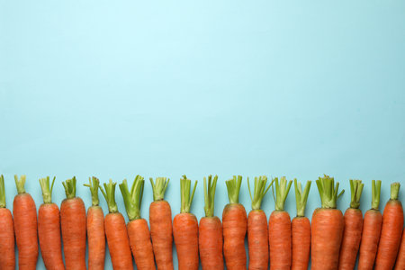 Flat lay composition with fresh carrots on color background. Space for text