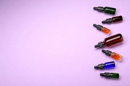 Bottles of essential oils on color background, flat lay with space for text. cosmetic productsの写真素材